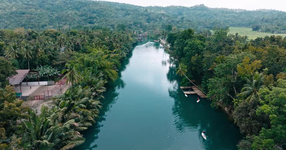 People enjoy the river while others play sports in a nearby structure