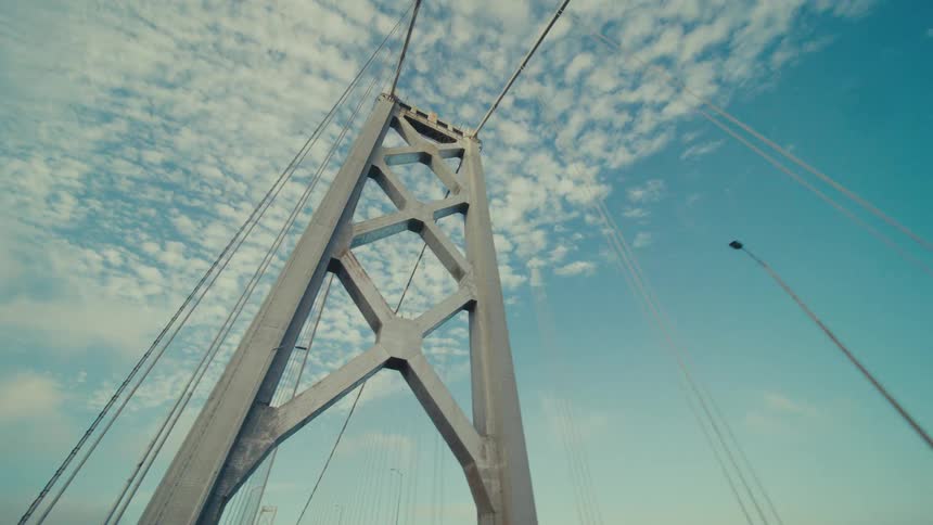 Cables spanning the gap between steel bridge supports under a blue sky
