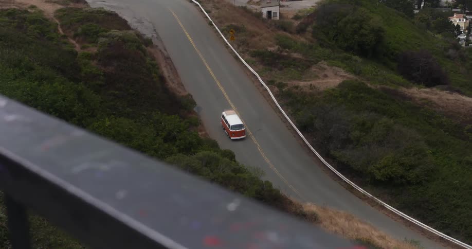 A red van driving down a road surrounded by trees