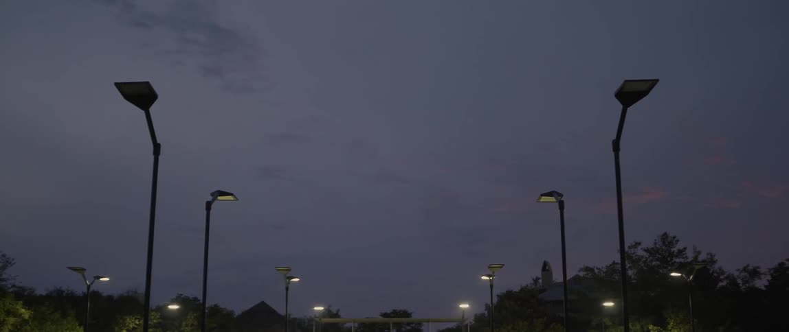 Street lights lit up at night with trees and a bridge