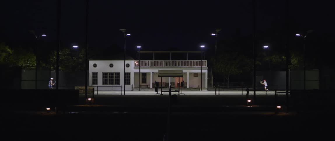 Two tennis players are having a match at night