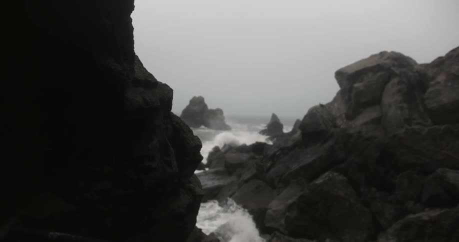 Waves crash against the rocks on a cloudy day
