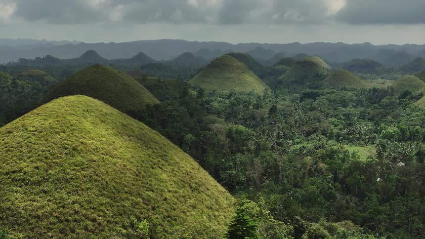 Aerial view of the famous chocolate hills in bohol philippines featuring hundreds of grasscovered limestone mounds rising symmetrically from the surrounding tropical forest