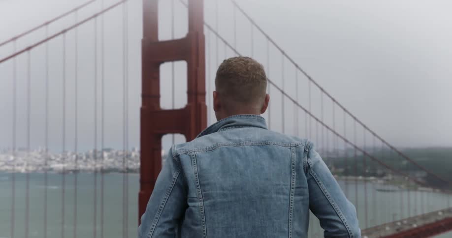 A man walks over to a view of the golden gate bridge