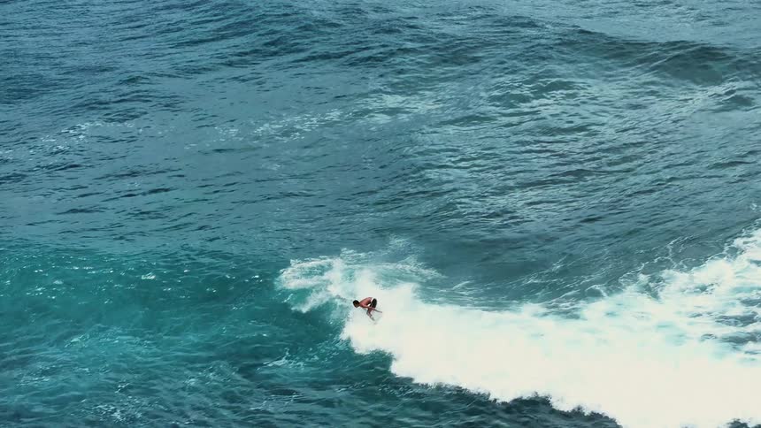 Aerial of surfer riding a wave in the ocean