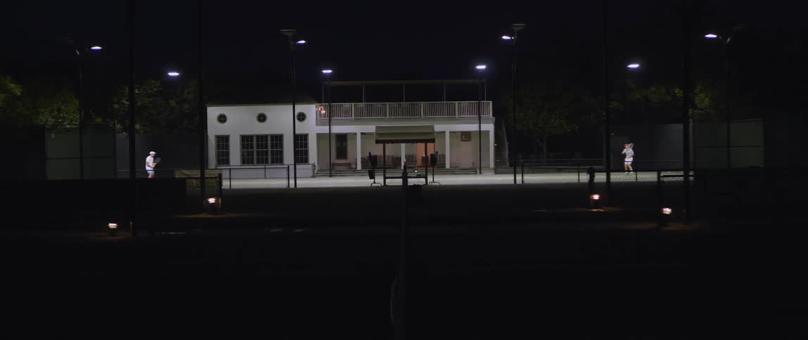 A man playing tennis in front of a building at night