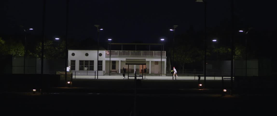 Two people are playing tennis at night