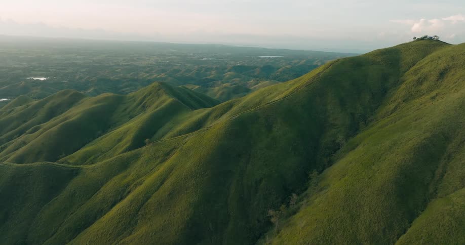 Mossy green mountains are shown in a vastly large area via aerial view