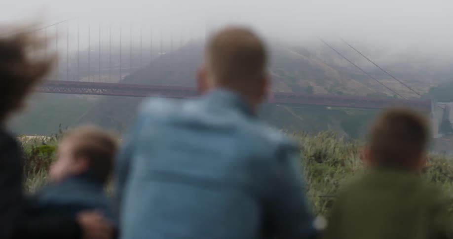 People are looking over at a large bridge on a windy day
