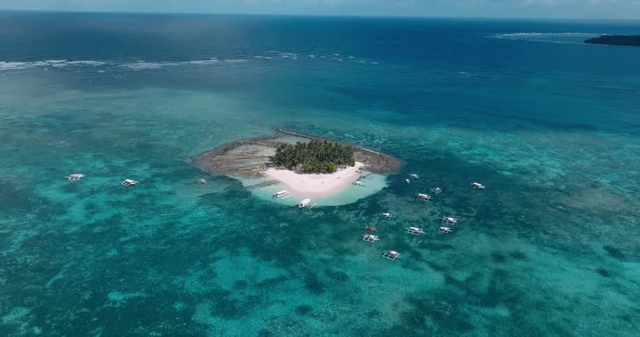 Boats leaving from and approaching a tropical island in the middle of the ocean
