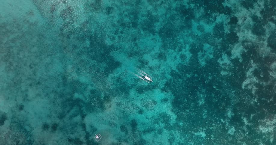 Boat travels in clear water over coral reefs