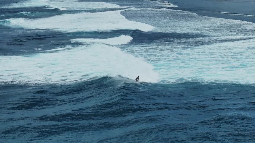 A surfer rides the tide towards the shore