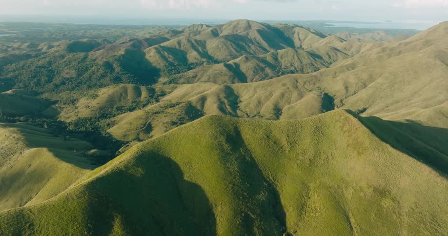 Grass covered mountains stretch to water in the distance