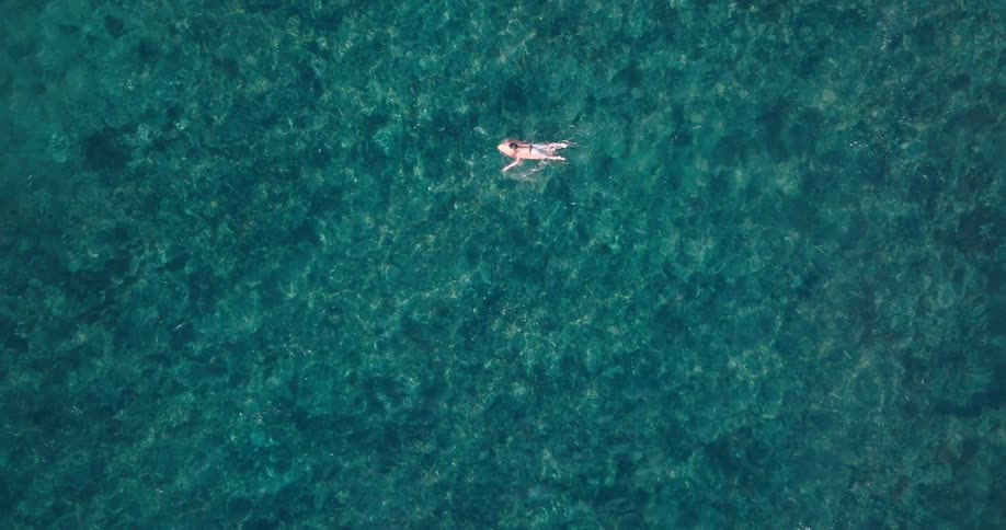 A man is paddling on a surfboard in the water