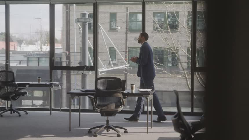 Man walks past the floor to ceiling windows of an office on a winter day