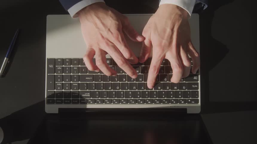 Overhead view of man typing on keyboard on laptop