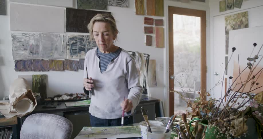 A woman is painting on a small canvas