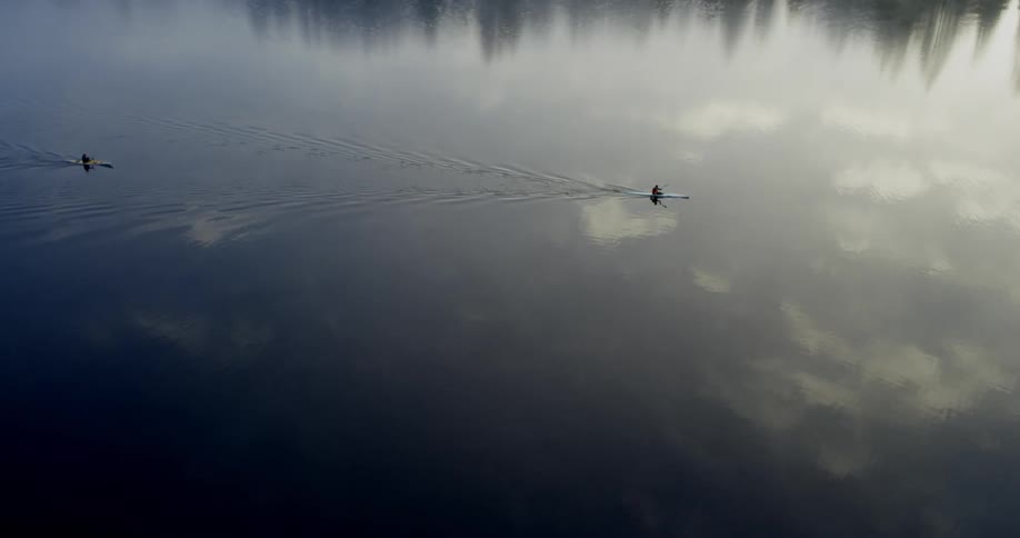 A couple of people paddling canoes in a body of water