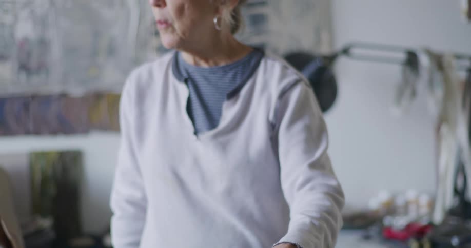 A woman is painting on a canvas inside her home