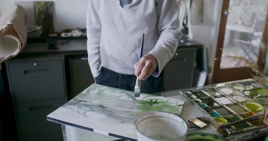 A woman paints with a canvas on the table