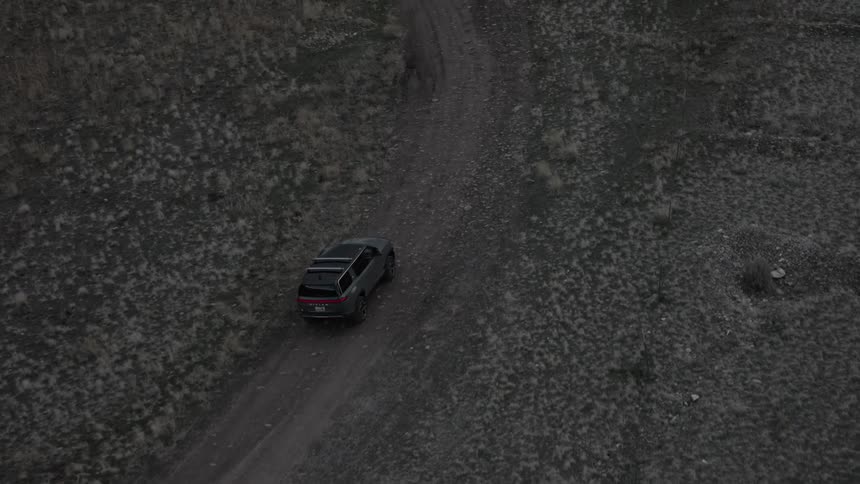 Vehicle drives toward a fork in the dirt road in the wilderness