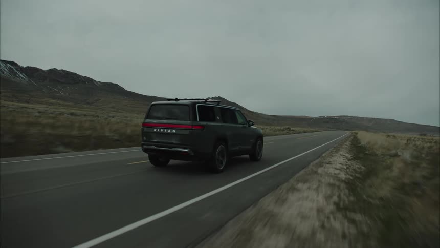 The vehicle is passing by the mountain on the road
