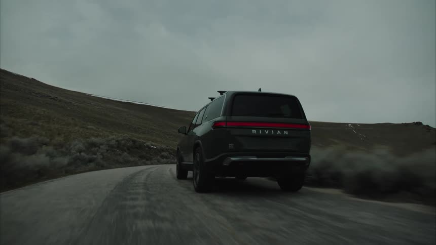 A vehicle is driving on the road by the hills