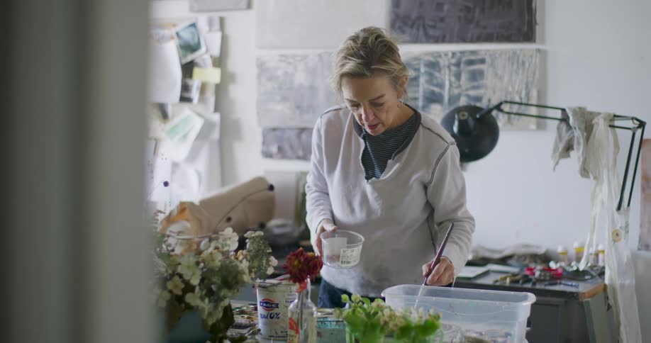 A woman is mixing paint in a cup