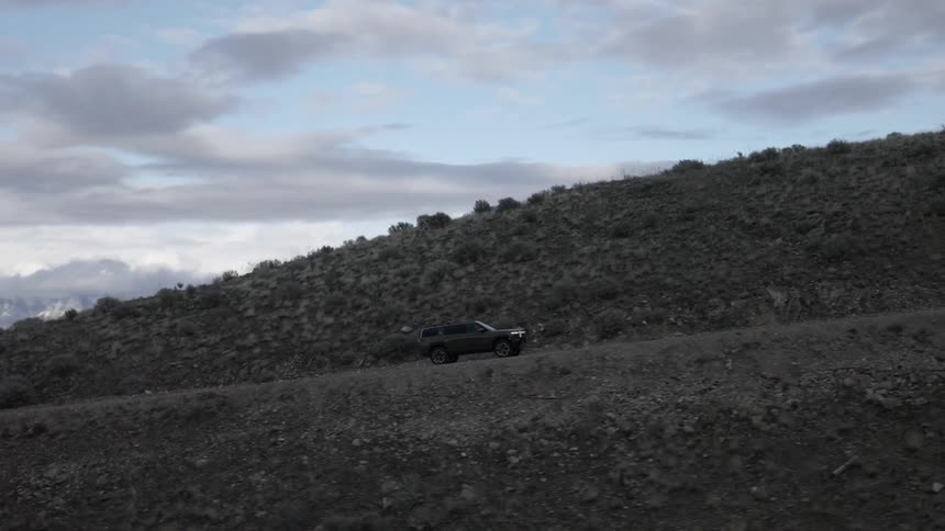 A sports utility vehicle drives up the mountain on a dirt road