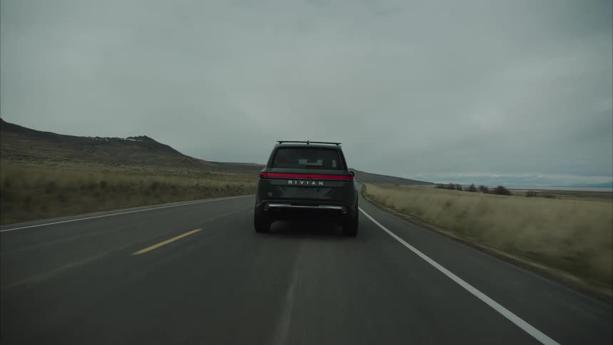Car driving down a twolane road toward the mountains