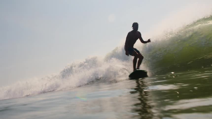 Surfer balances on his surfboard as he rides a wave into shore