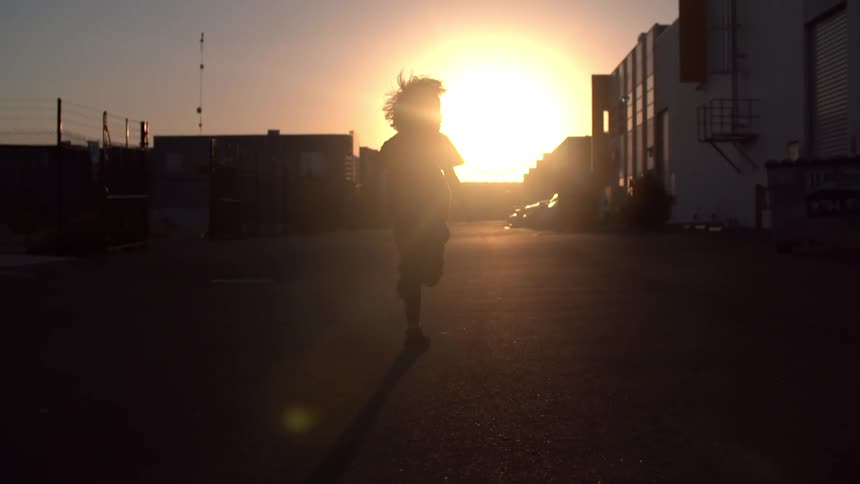 Child runs on pavement at sunset