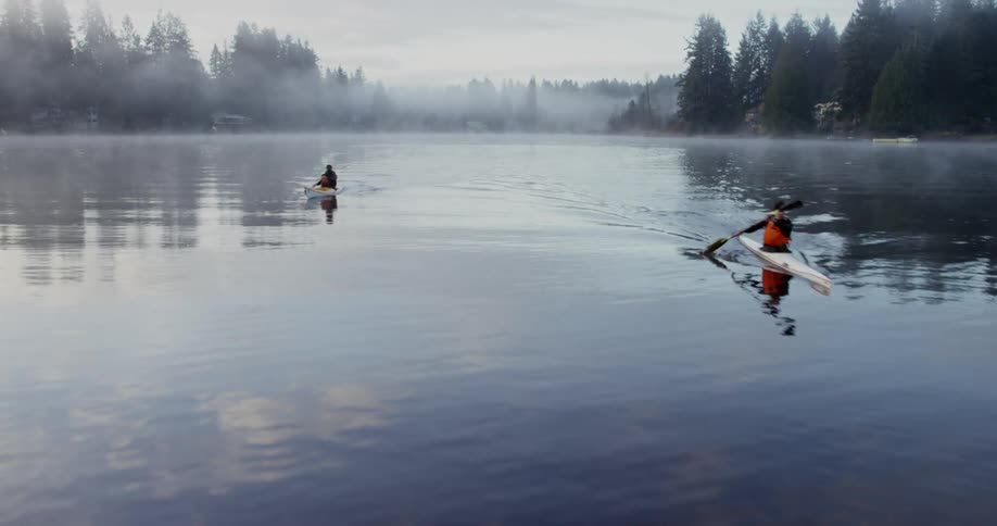 Two people paddle their canoes in the water