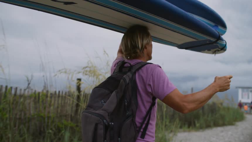 A footage of a person carrying a surfboard