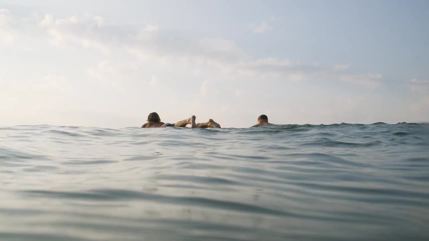 Two men are swimming on their surfboards