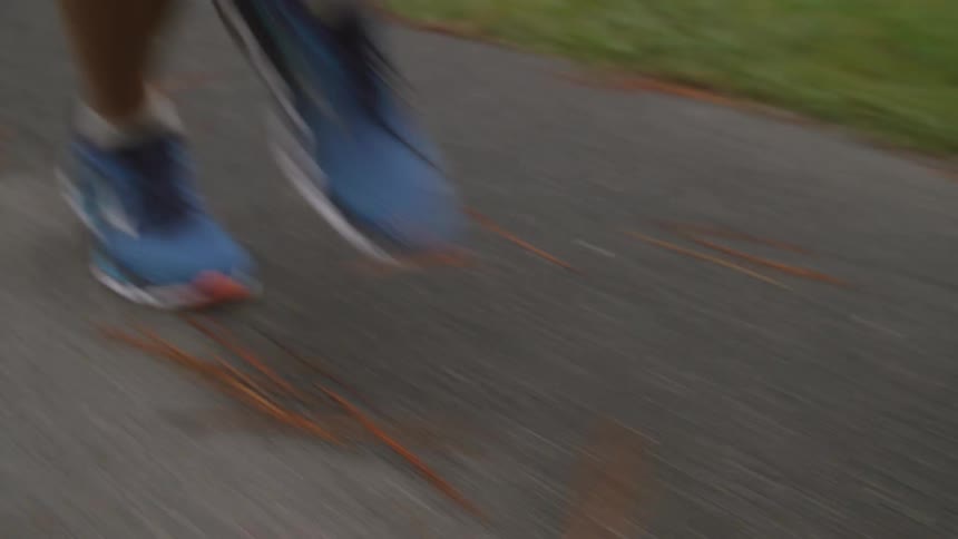 Man jogs along a paved path during a summer day