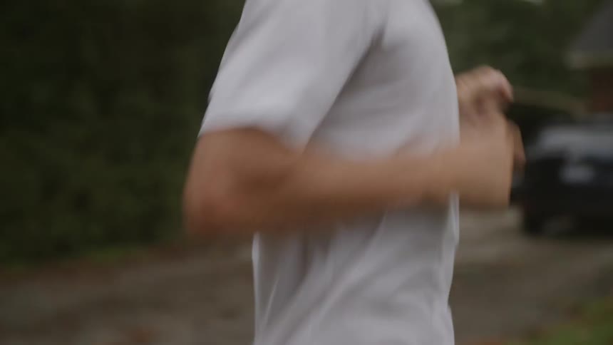 Close up of man in white tshirt jogging through a neighborhood