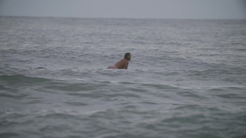 A man is surfing in ocean water on a windy day