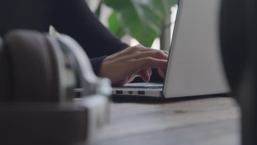 A person is typing fast on their laptop in a room