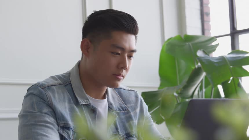 A man is working at his laptop near the window