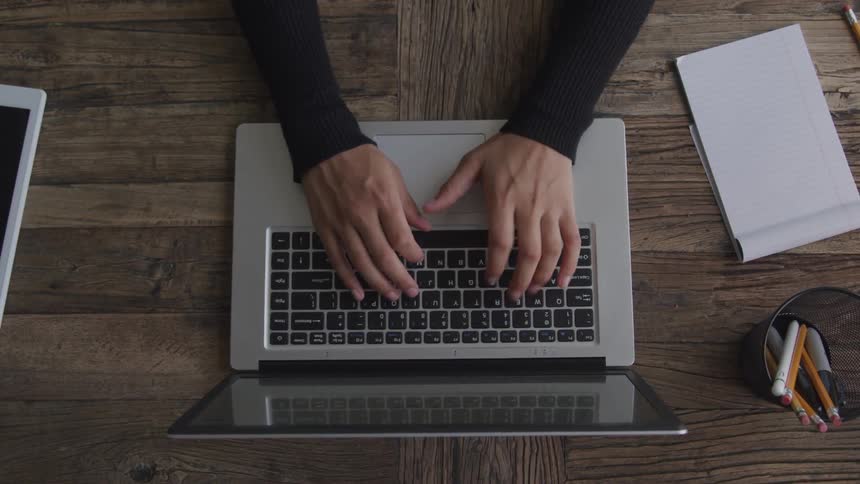 Overhead view person typing on keyboard on laptop