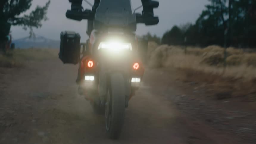 A man is driving his motorcycle on a dirt trail