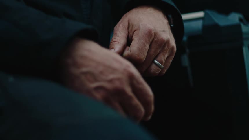 A man is holding his hands on his lap