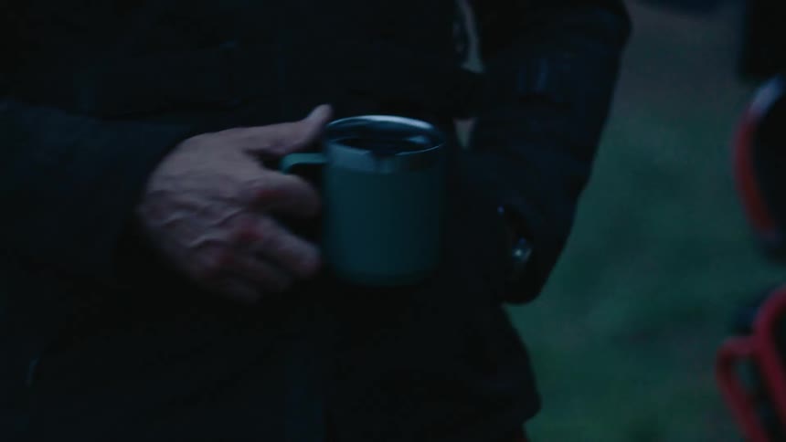 Standing outdoors a person is holding a coffee cup