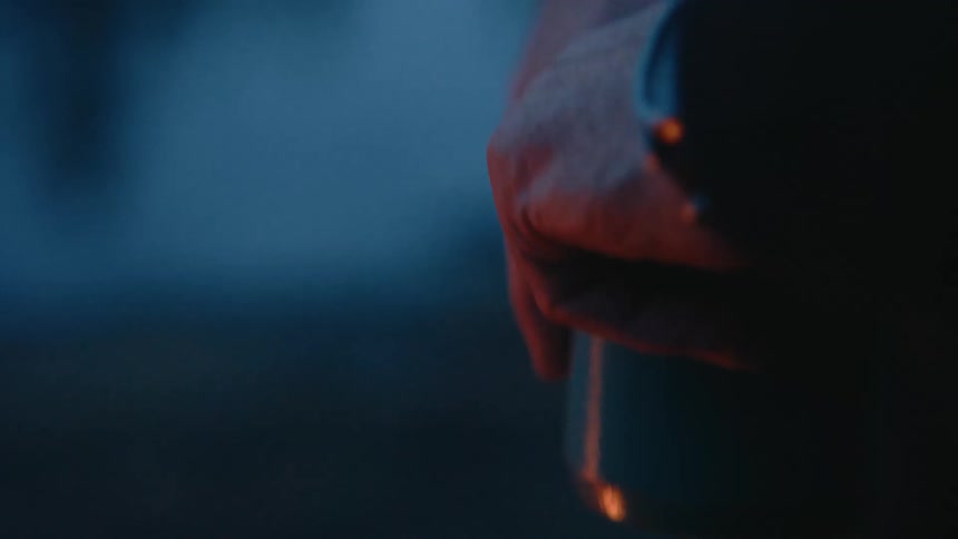 The campfire flickers light on the man