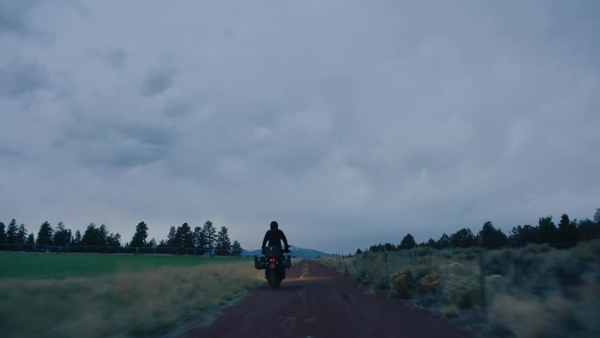 A man is riding a motorcycleon a dirt road