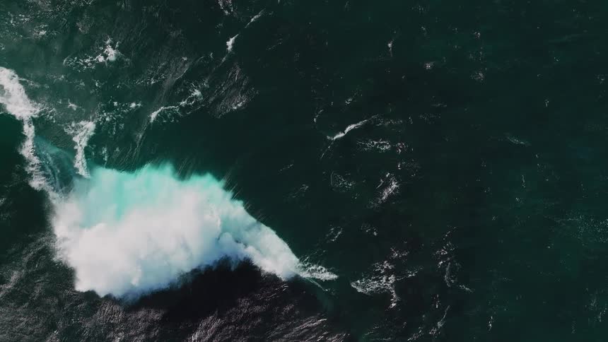 Aerial of a wave forming and crashing in the ocean