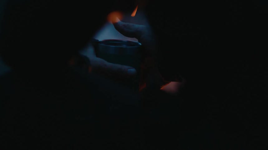 A person stands up from the campfire