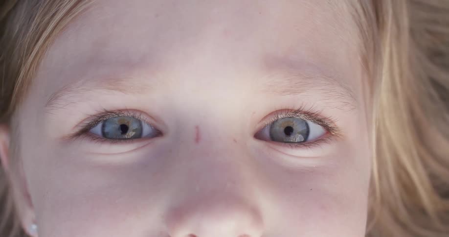 A girl looks straight ahead unblinking