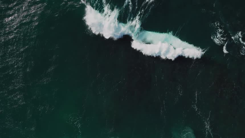 A big wave splashing in the ocean creating lots of foam